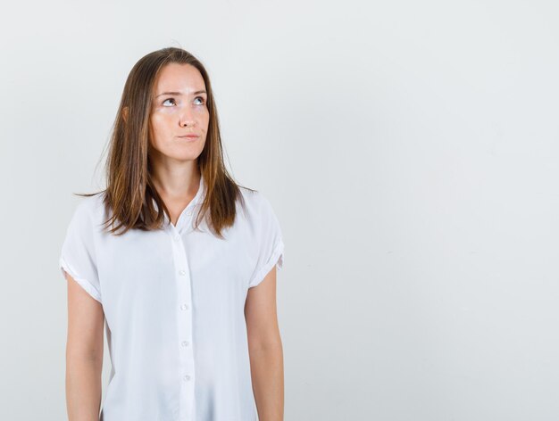 Young female looking away in white blouse and looking displeased.