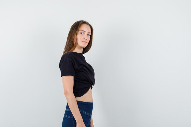 Young female looking at camera in black blouse, pants and looking cute.