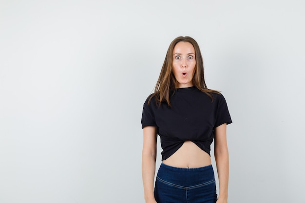 Free photo young female looking at camera in black blouse, pants and looking surprised