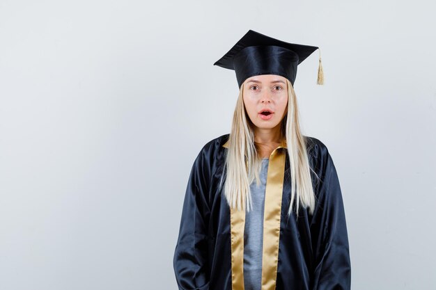 Young female looking at camera in graduate uniform and looking shocked