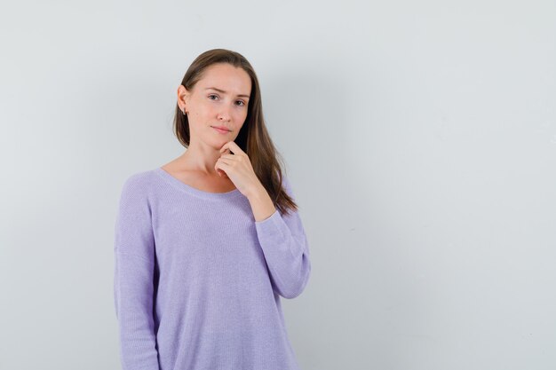 Young female looking at camera in lilac blouse and looking emotional 