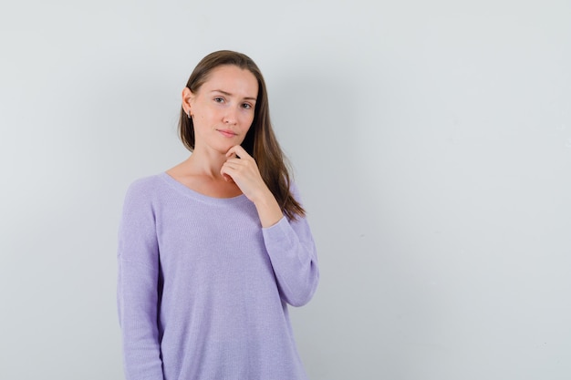 Young female looking at camera in lilac blouse and looking emotional 