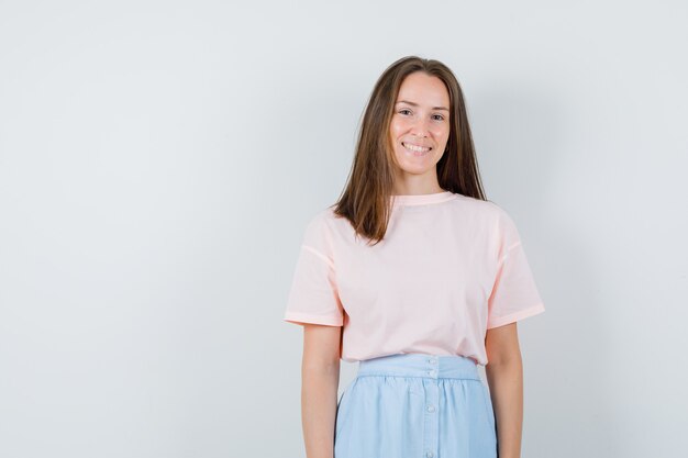 Young female looking at camera in t-shirt, skirt and looking glad , front view.