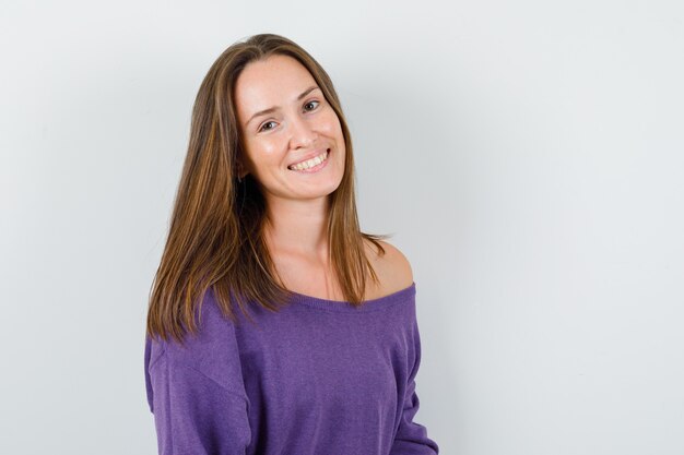 Young female looking at camera in violet shirt and looking cheerful. front view.