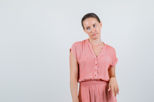 Young female looking down in striped dress and looking focused. front view.