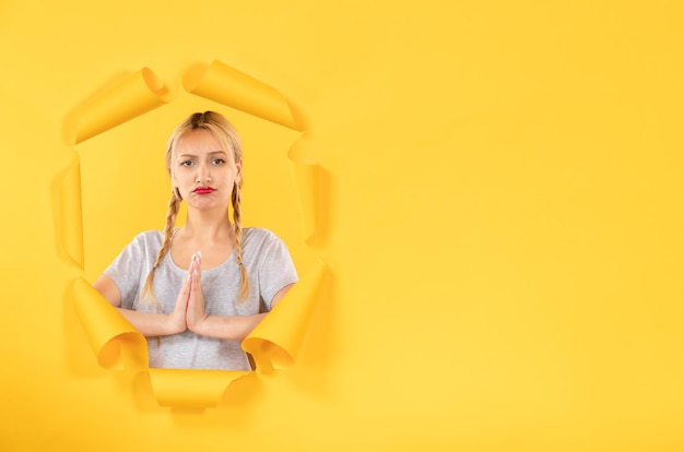 Young female looking from torn yellow paper background indoor window sale