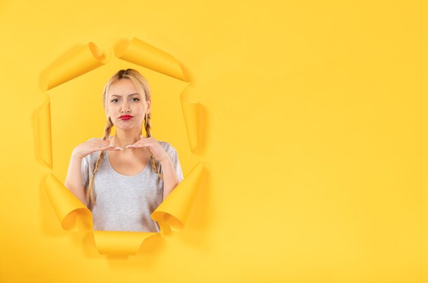 Young female looking from torn yellow paper background sale indoor window facials