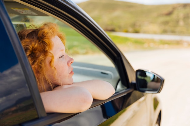 車の窓の外を見て若い女性