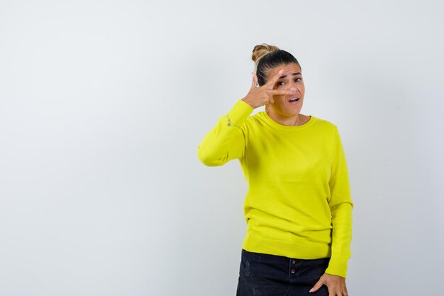 Young female looking through fingers in sweater, denim skirt and looking confident 