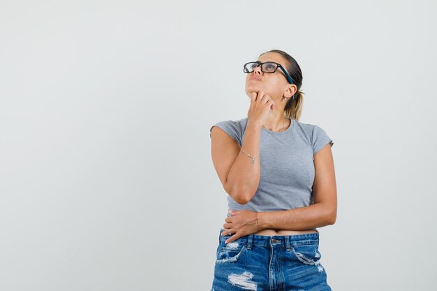 Young female looking up in t-shirt, shorts and looking pensive