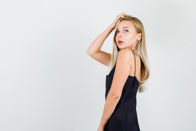 Young female looking up with hand on hair in black singlet and looking attractive