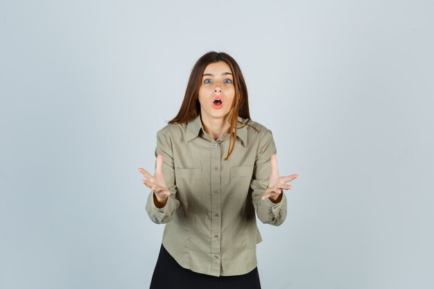 Young female making asking question gesture in shirt, skirt and looking shocked. front view.