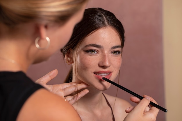 Бесплатное фото Молодая женщина-модель делает макияж профессионального художника