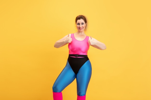 Young female model training on yellow wall