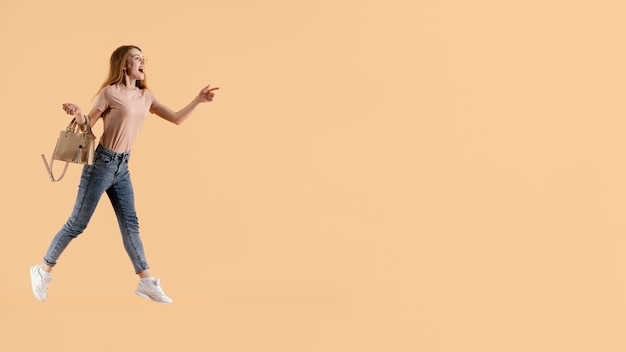 Free photo young female model with hand bag jumping