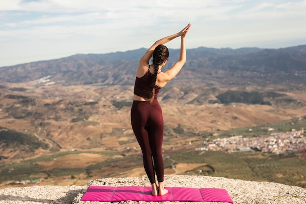 Giovane femmina sull'yoga di pratica della montagna