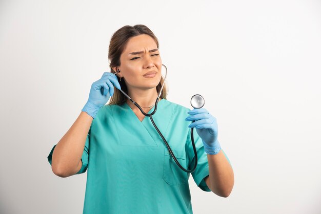 Young female nurse looking on stethoscope.