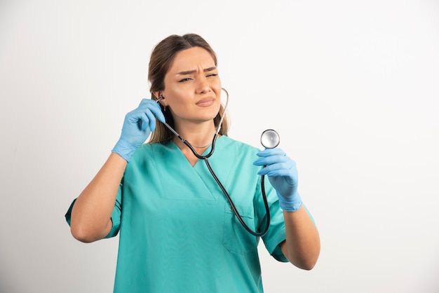 Young female nurse looking on stethoscope.