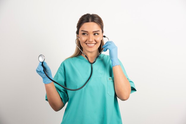 Молодая медсестра со стетоскопом на белом фоне