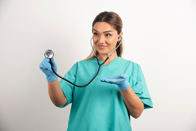 Young female nurse with stethoscope on white background