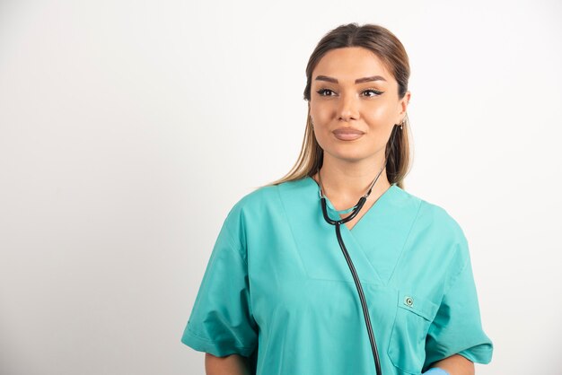 Young female nurse with stethoscope on white background