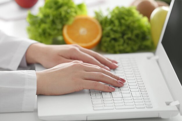 Young female nutritionist working on laptop in office, close up