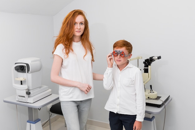 소년 환자의 눈을 검사하는 동안 카메라를보고 젊은 여성 안경점