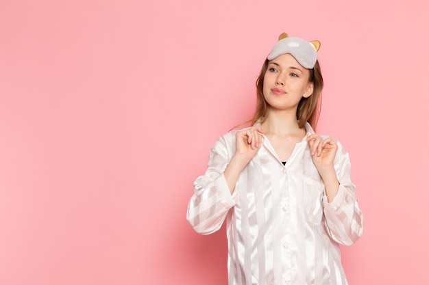 Free photo young female in pajamas and sleep mask posing on pink