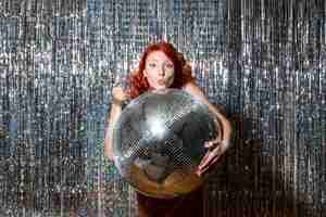 Foto gratuita giovane donna in festa con palla da discoteca su tende luminose