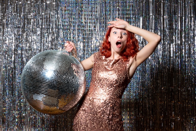 Free photo young female in party with disco ball on bright curtains