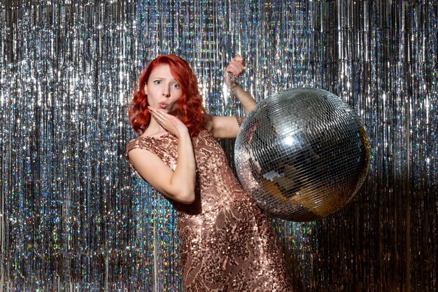 young female in party with disco ball on bright curtains