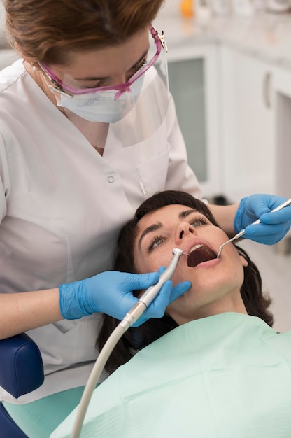 Foto gratuita giovane paziente femminile che ha procedura dentale all'ortodontista