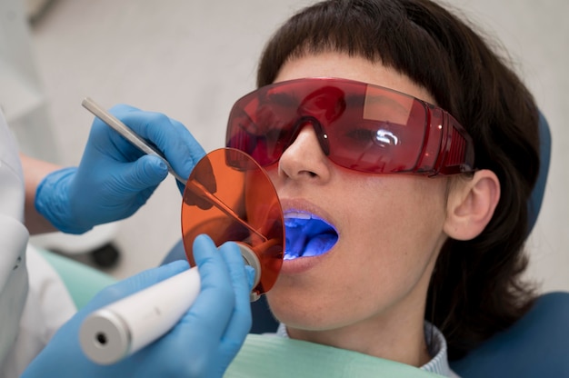 Foto gratuita giovane paziente femminile che ha procedura dentale all'ortodontista