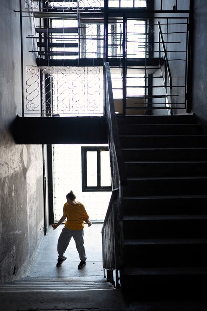 Young female performer dancing in an abandoned building on stairs