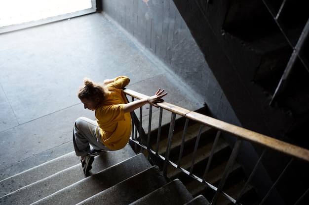 Young female performer dancing in an abandoned building on stairs