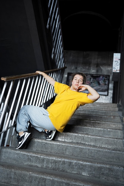 Young female performer dancing in an abandoned building on stairs