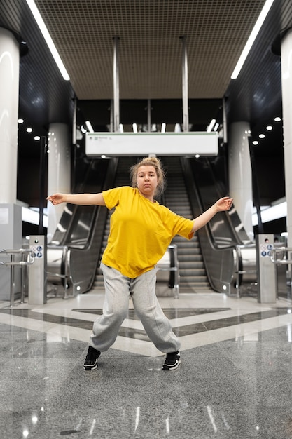 Young female performer dancing at a subway station on front of escalators