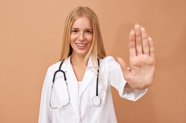 Young female physician with straight blonde hair and stethoscope around her neck asking to stop