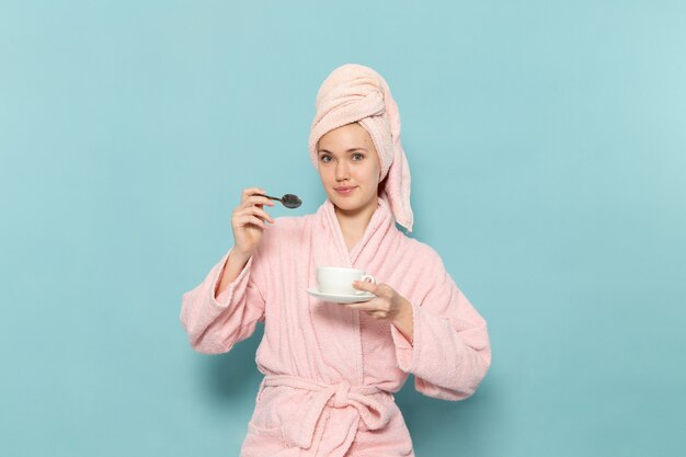 young female in pink bathrobe after shower on blue
