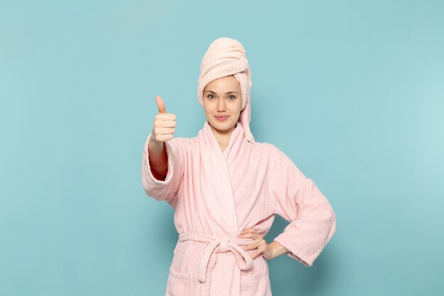 young female in pink bathrobe after shower posing with smile face on blue