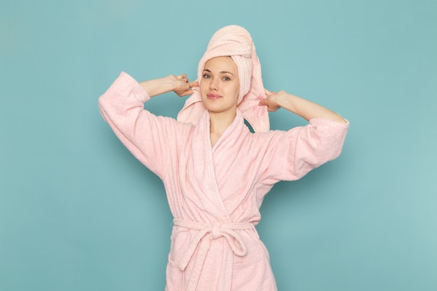 Free photo young female in pink bathrobe after shower smiling on blue