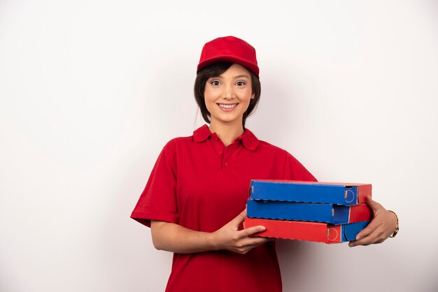 Young female pizza delivery worker holding three cardboards of pizza.