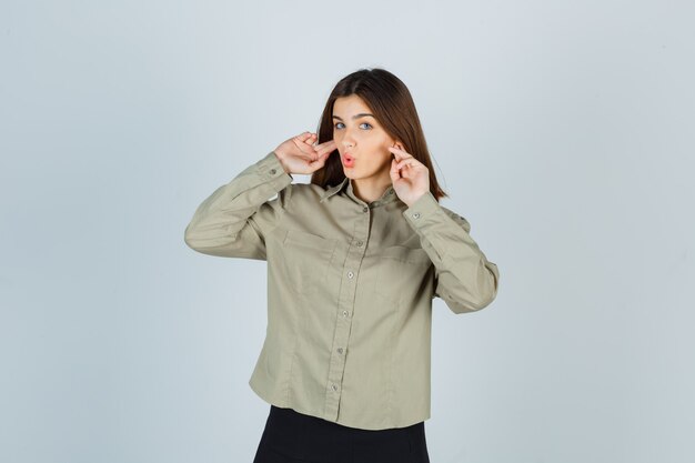 Young female plugging ears with fingers, keeping lips folded in shirt