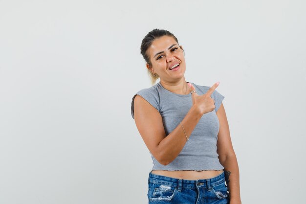 Young female pointing away in t-shirt, shorts and looking cheery