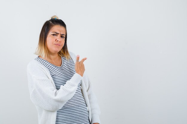 若い女性がTシャツ、カーディガンを振り返り、動揺しているように見えます。正面図。