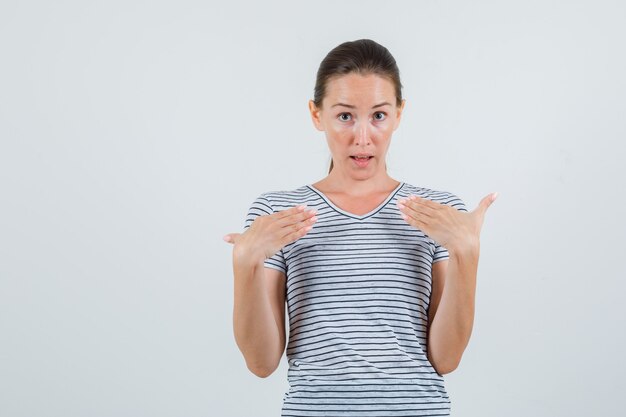 Young female pointing at herself in striped t-shirt front view.