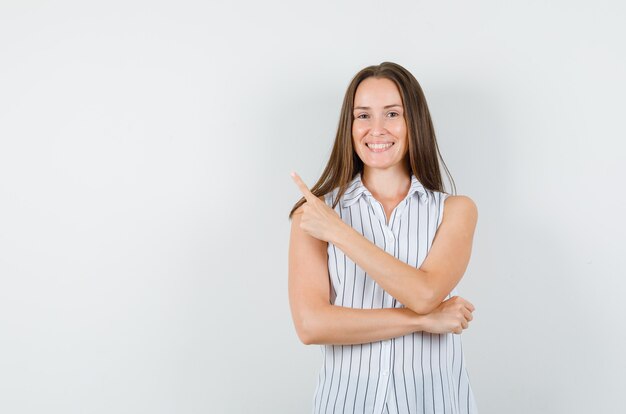 Young female pointing up in t-shirt and looking happy. front view.