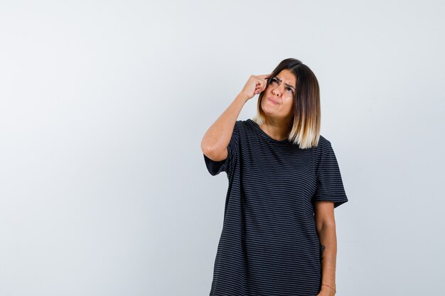 Young female in polo dress standing in thinking pose and looking thoughtful , front view.