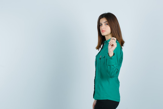 녹색 셔츠에 손을 올리고 매혹적인 찾고있는 동안 포즈를 취하는 젊은 여성.
