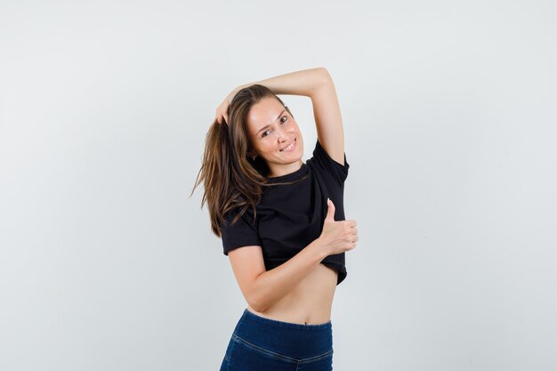 Young female posing while showing thumb up in black blouse